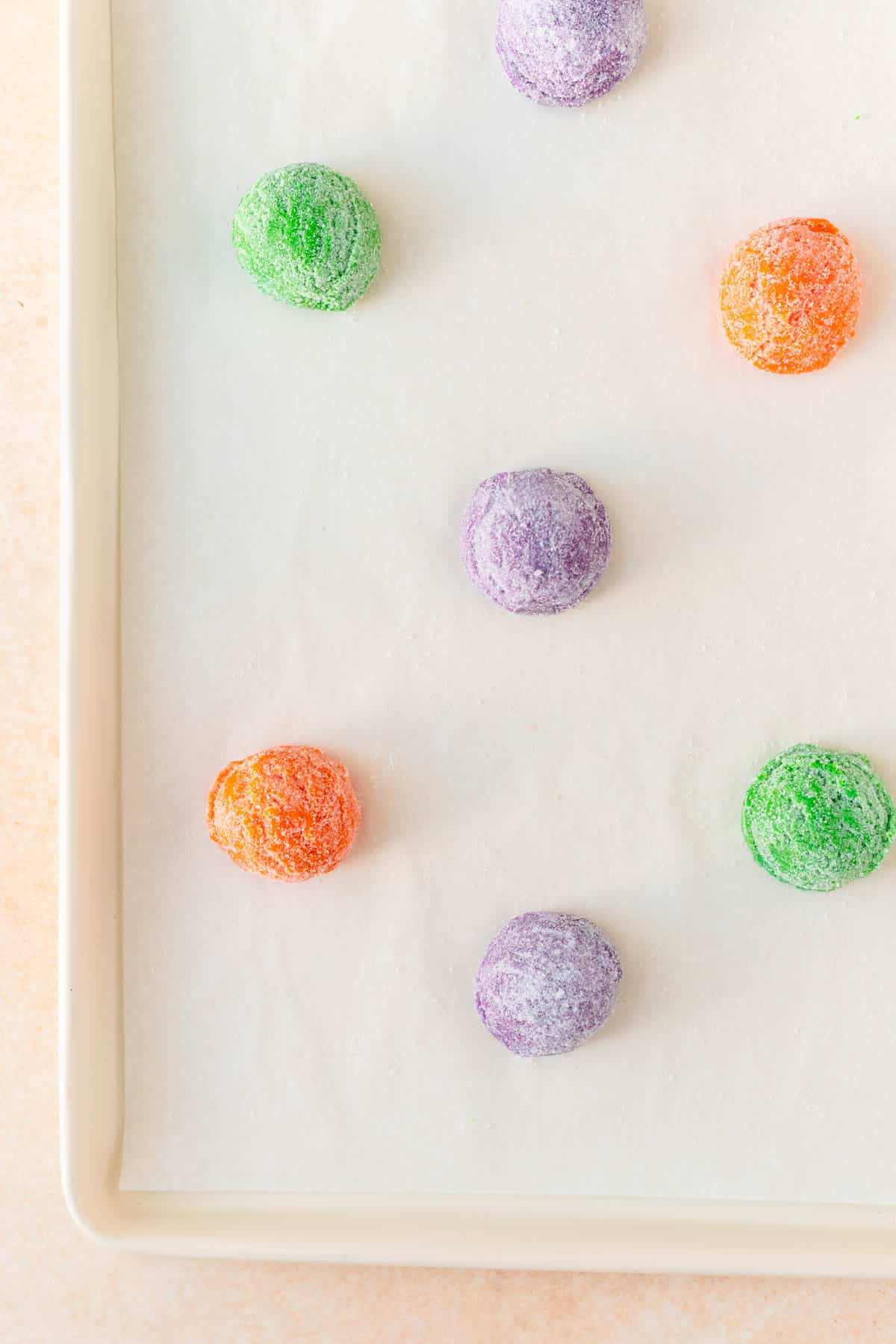 purple green and orange dough balls on top of a white baking sheet