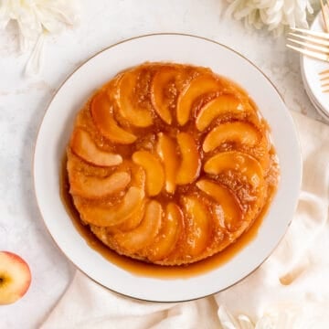 apple upside down cake on a white with an apple and white mums around it