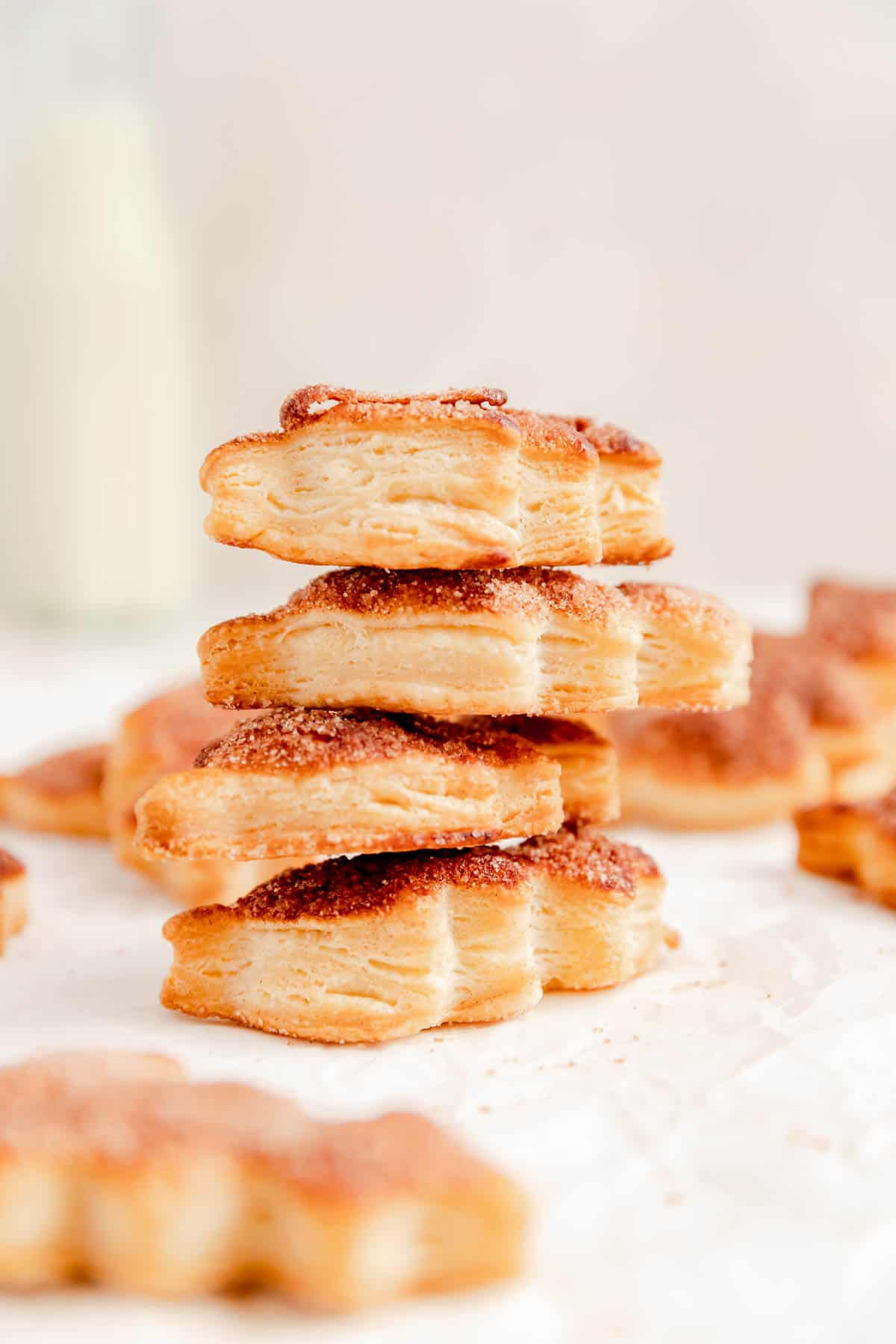 a stack of 4 pie dough cookies with other in the back and foreground