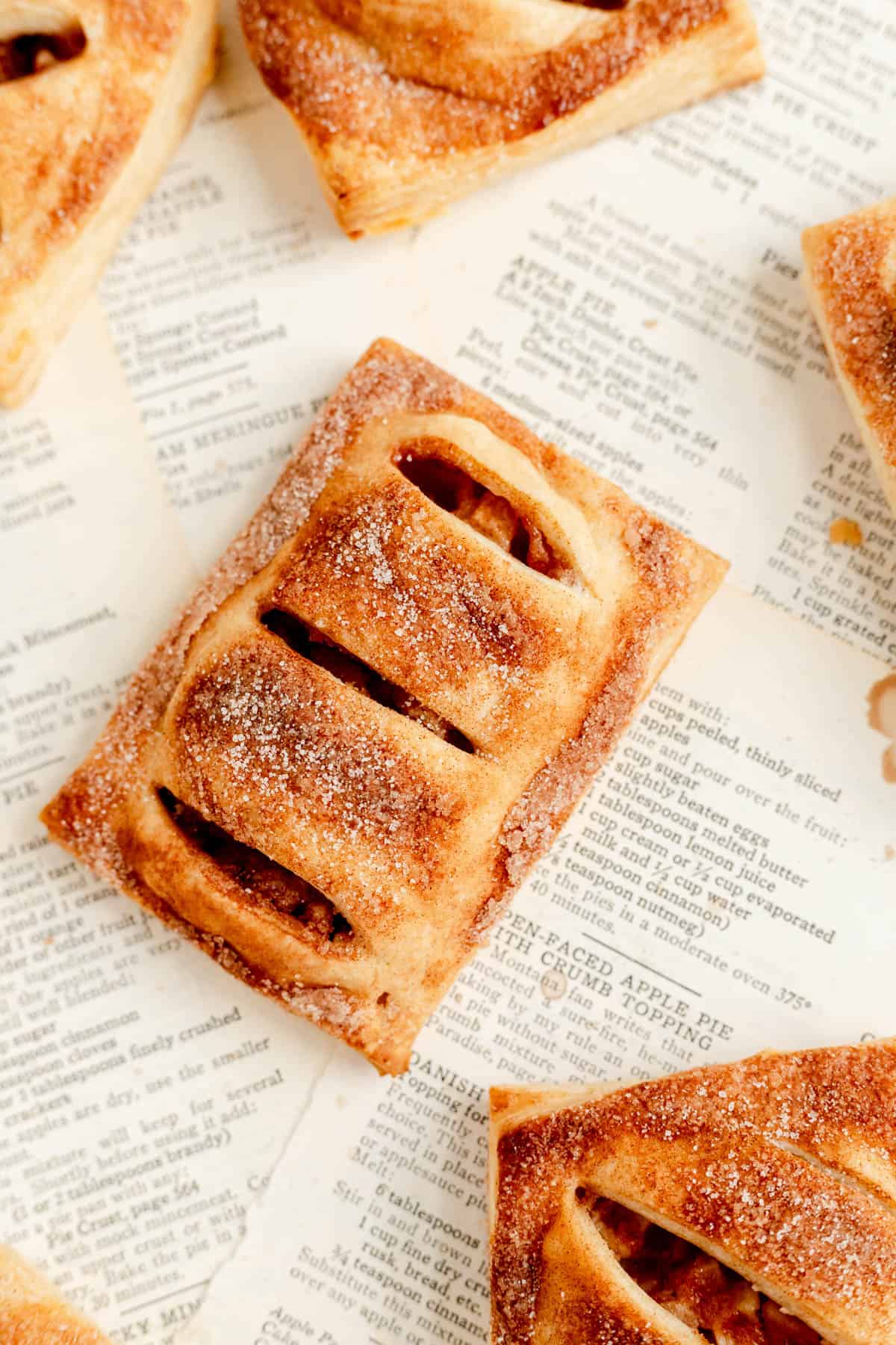 a close up of an apple hand pie, surrounded by other pies on vintage recipe pages