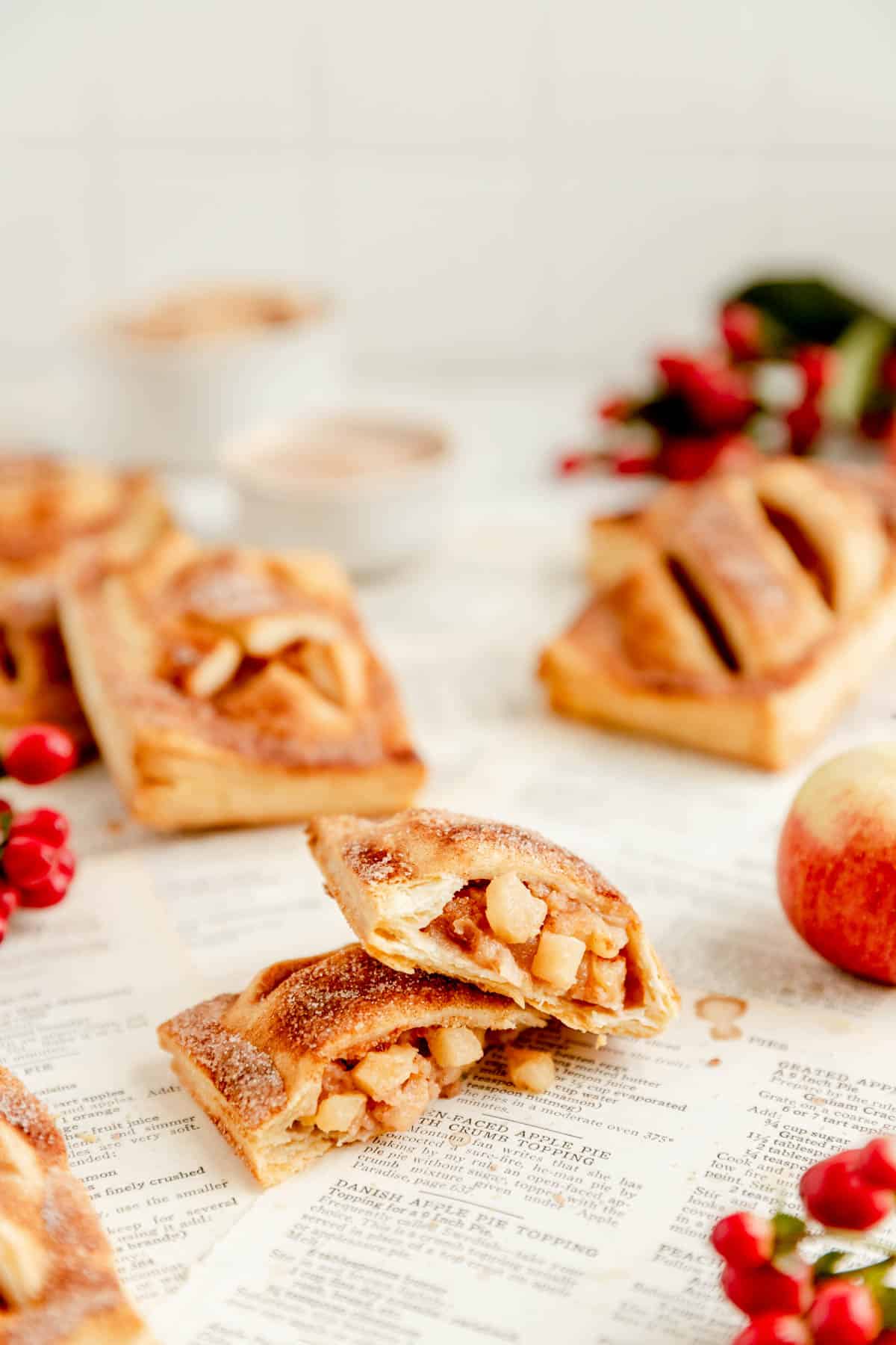 an open apple hand pie with two halves stack on each other on recipe book pages