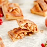 an open apple hand pie with two halves stack on each other on recipe book pages