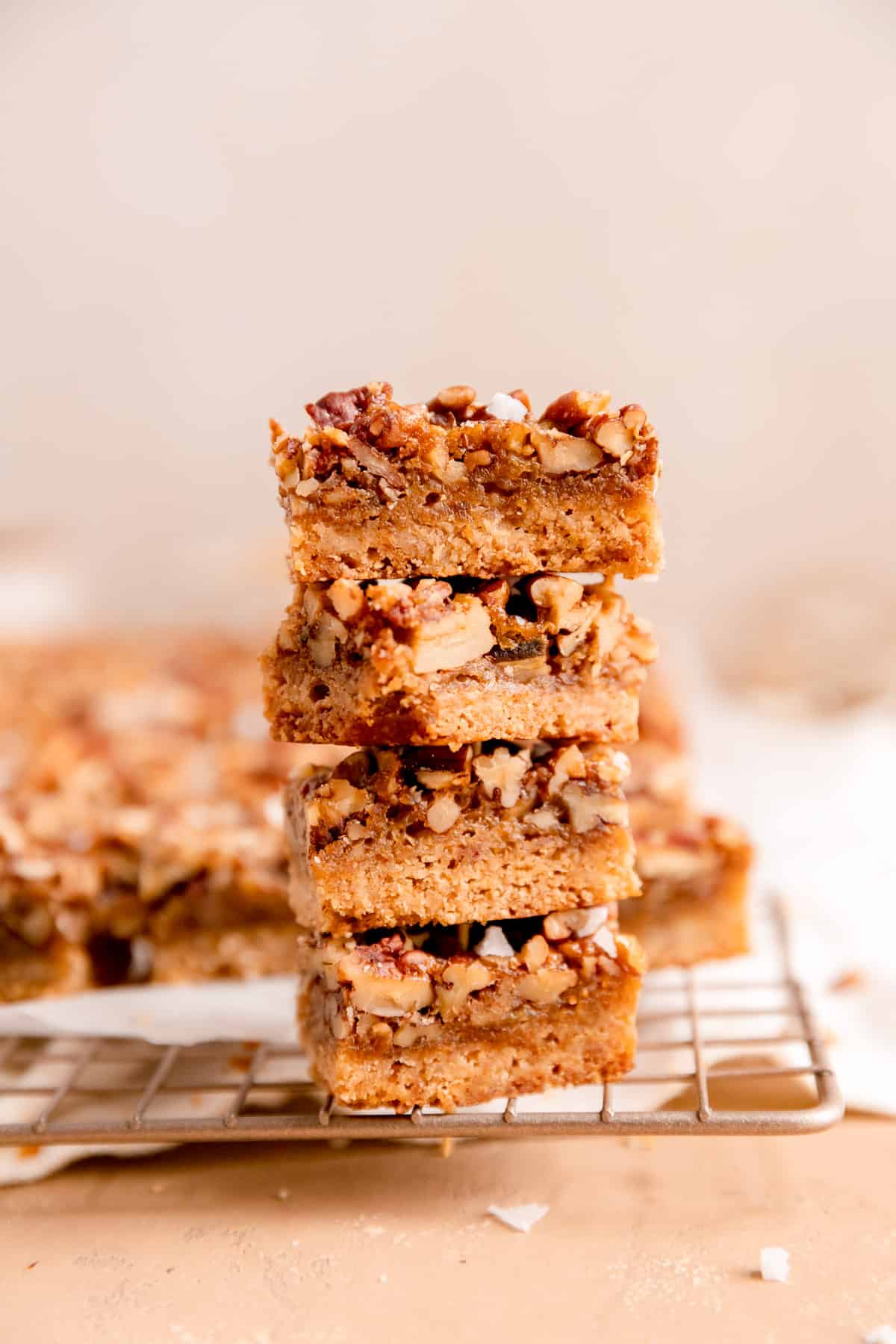 a side view of a stack of pecan pie bars on a gold cooling rack