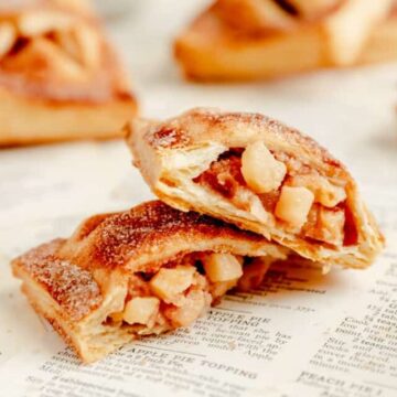 an open apple hand pie with two halves stack on each other on recipe book pages