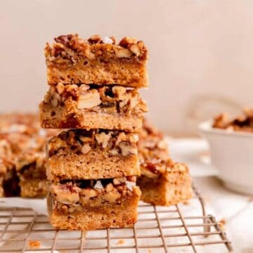 a side view of a stack of pecan pie bars on a gold cooling rack