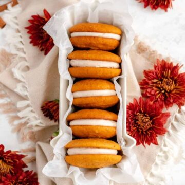 overhead shot of 5 pumpkin whoopie pies on their side with red mums on the table