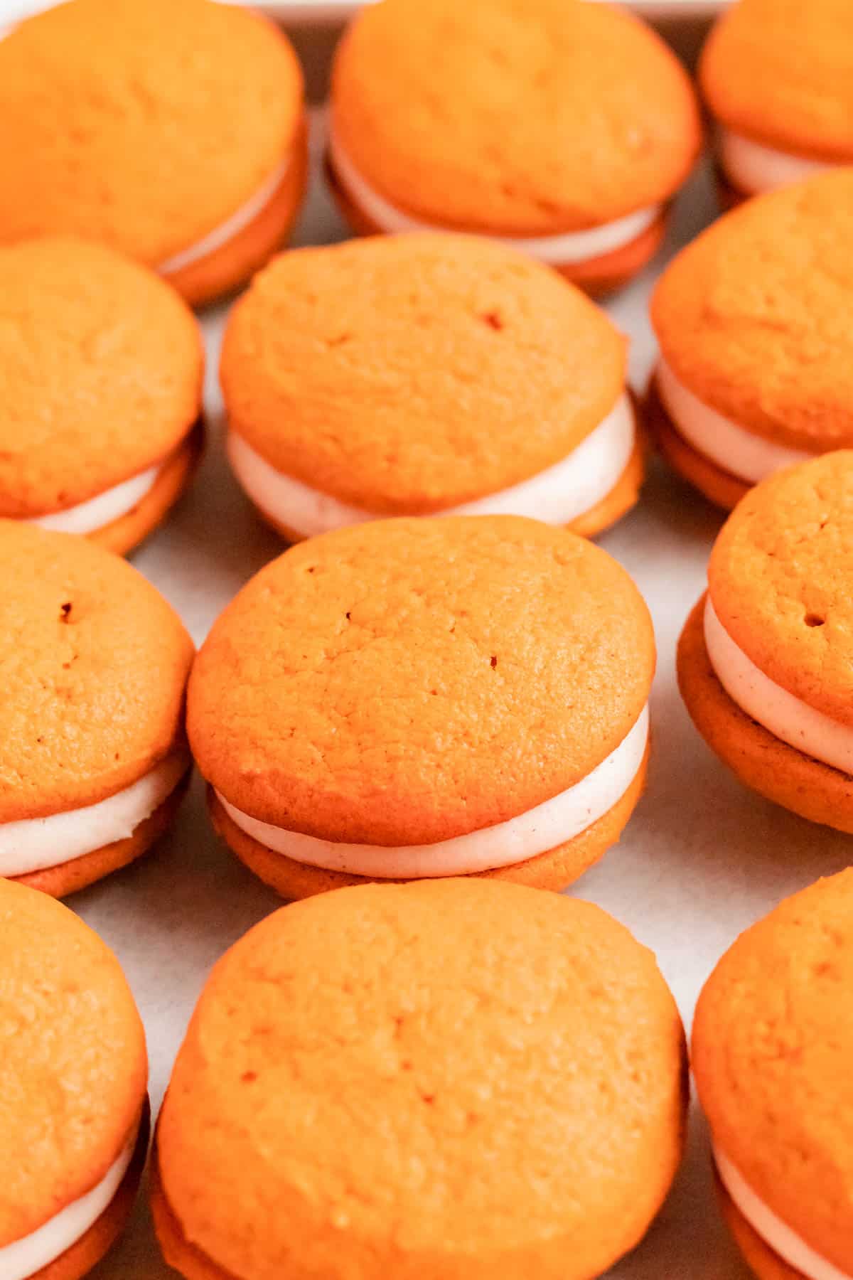 close up of fully filled and assembled pumpkin whoopie pies with cream cheese filling