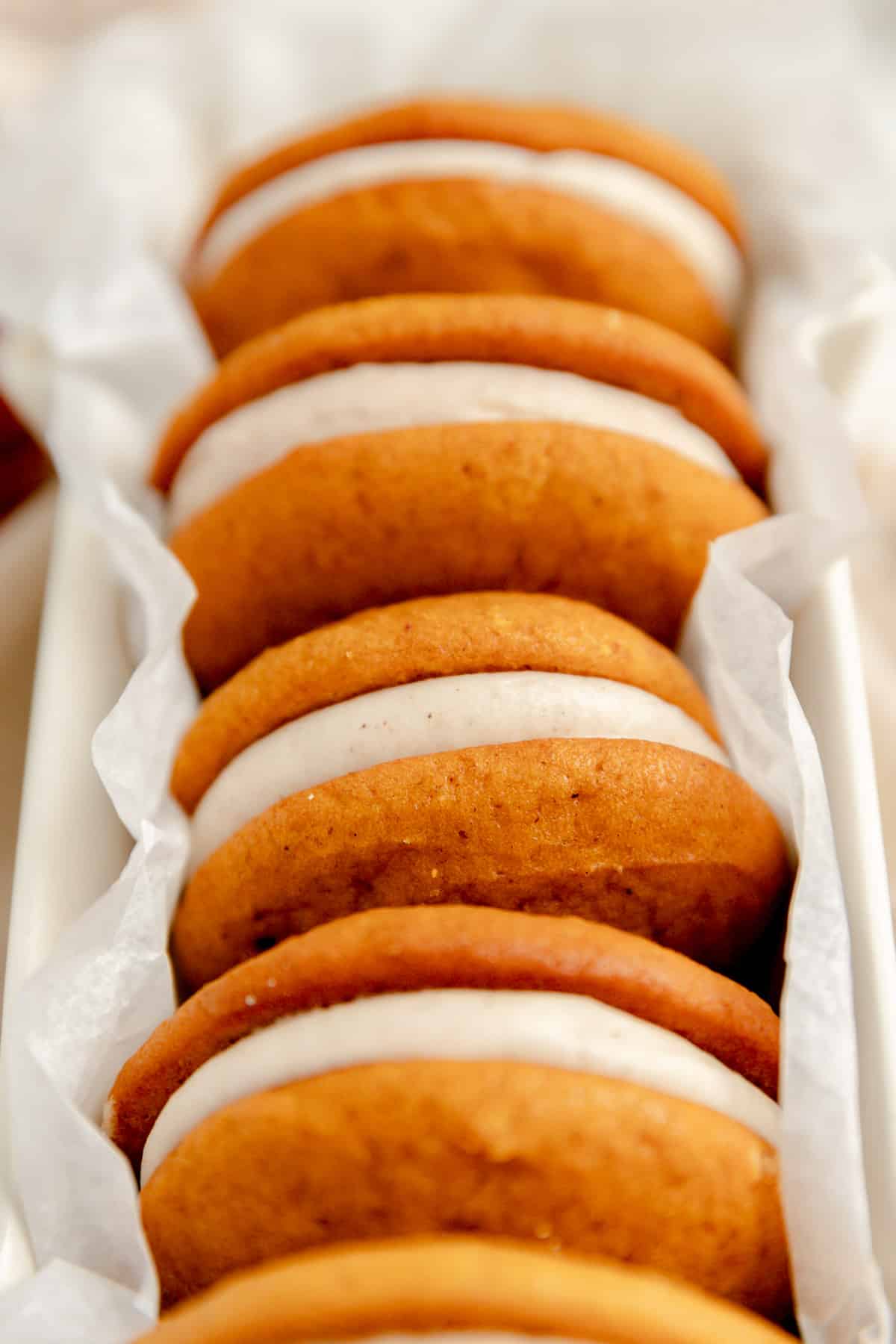 a close up of pumpkin whoopie pies with cream cheese filling on their sides