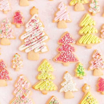 Overhead view of pink white and green Christmas tree sugar cookies in various sizes