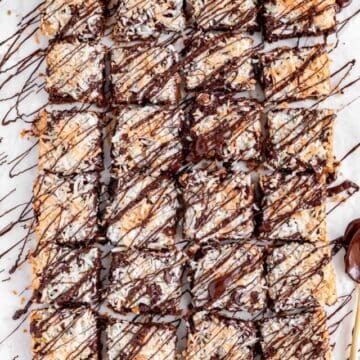 Overhead view of a full pan of chocolate drizzled magic bars with balls of ingredients on side