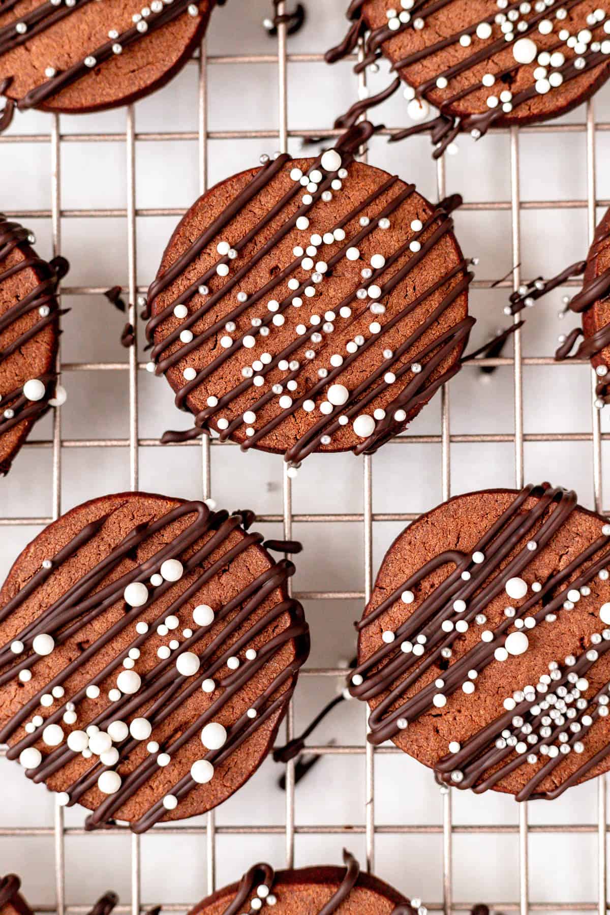 close up of chocolate butter cookies with chocolate drizzle and white sprinkles.