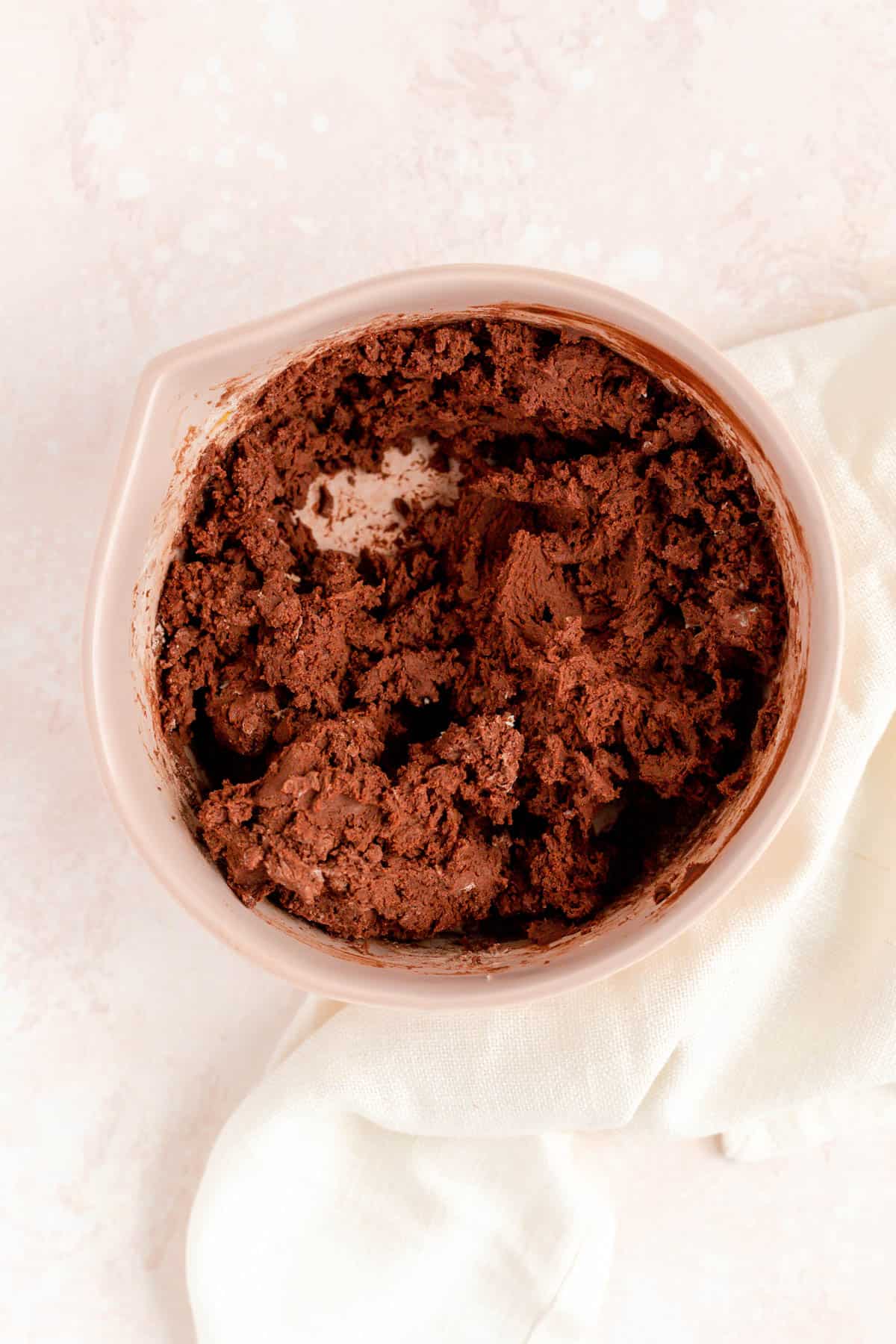 Chocolate butter cookie dough mixed in a brown bowl on a pink background