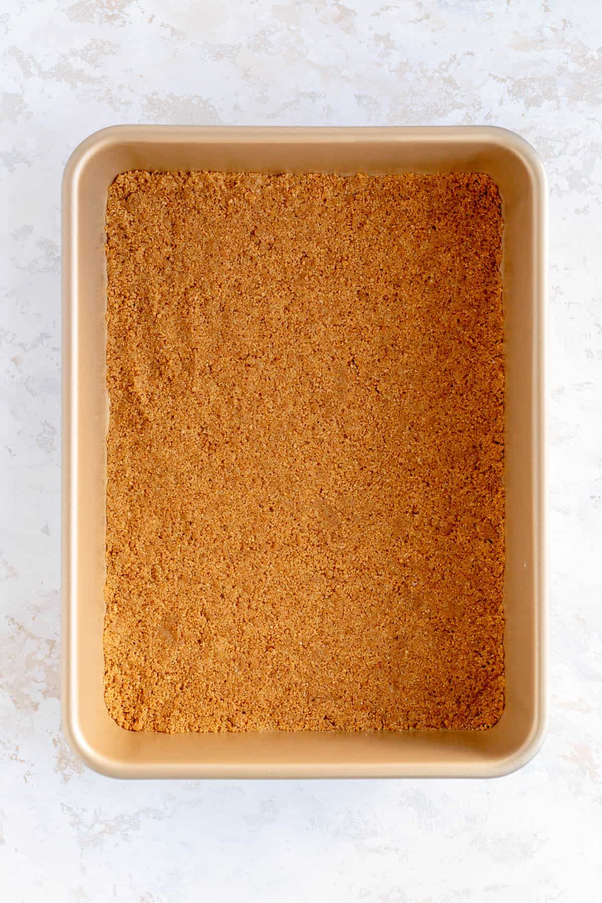 a pressed graham cracker crust in a gold 9 x 13 pan