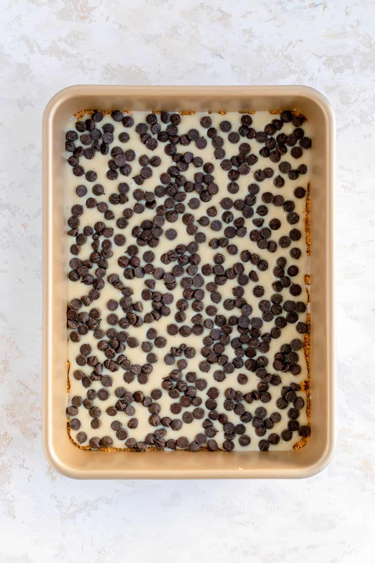 Chocolate chips in condensed milk in a 9 x 13 gold pan