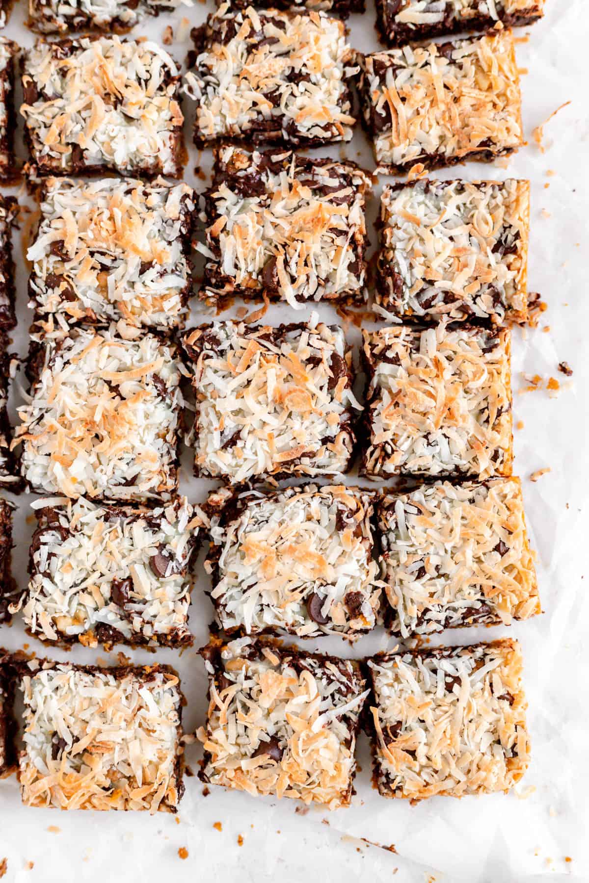 Toasted coconut seven layer magic bars cut and spaced out on parchment