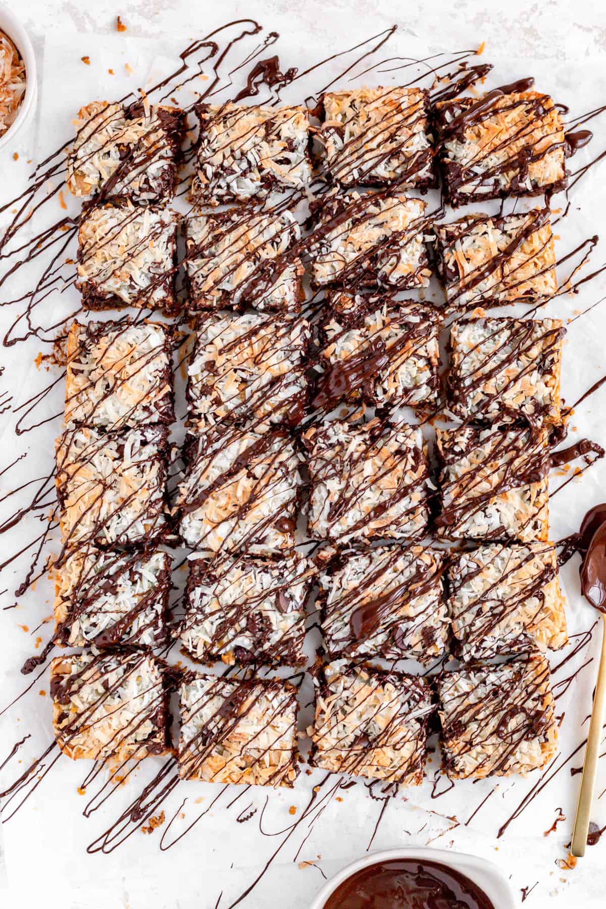 Overhead view of a full pan of chocolate drizzled magic bars with balls of ingredients on side