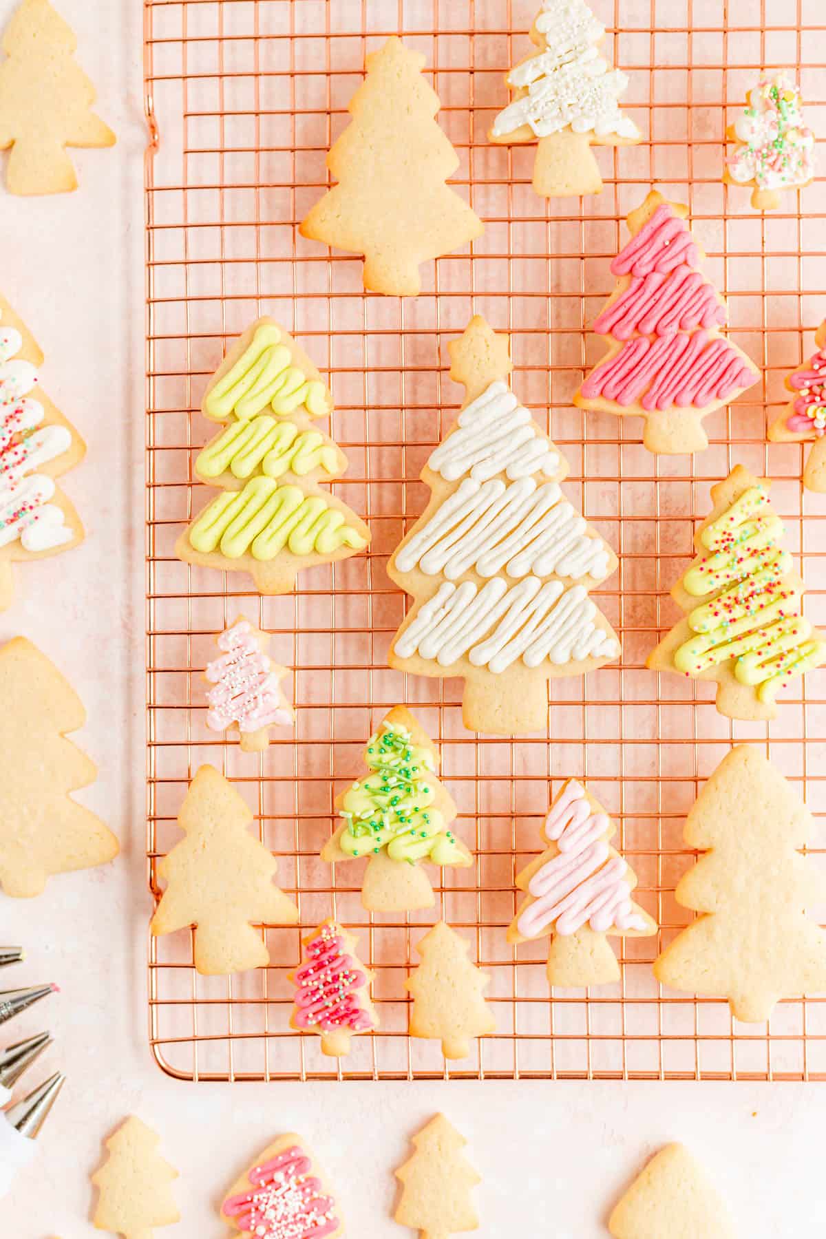 Frosted and frosted and decorated Christmas tree sugar cookies on a copper wire rack