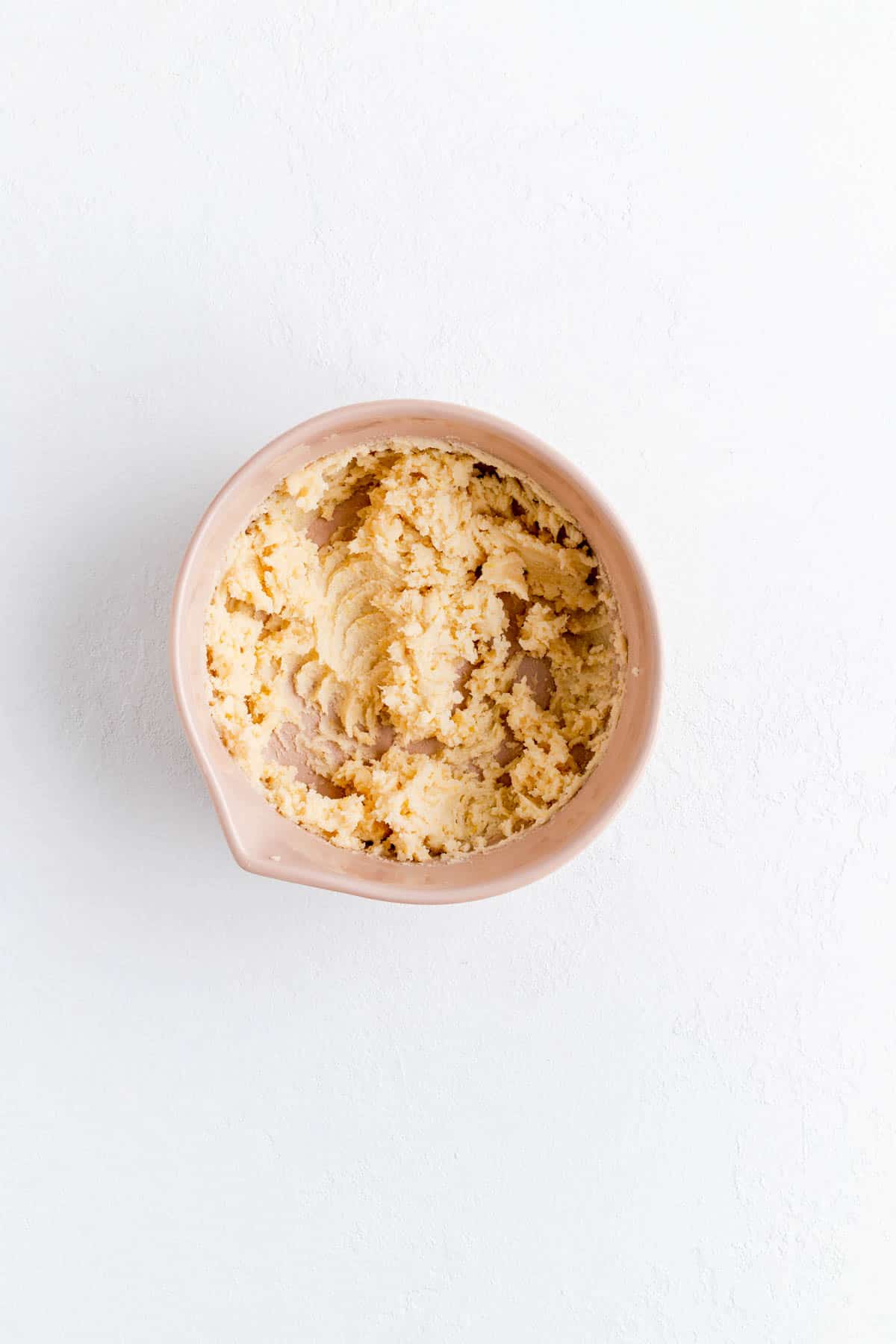 Butter and sugar creamed for cupcakes and a tan bowl on white background.