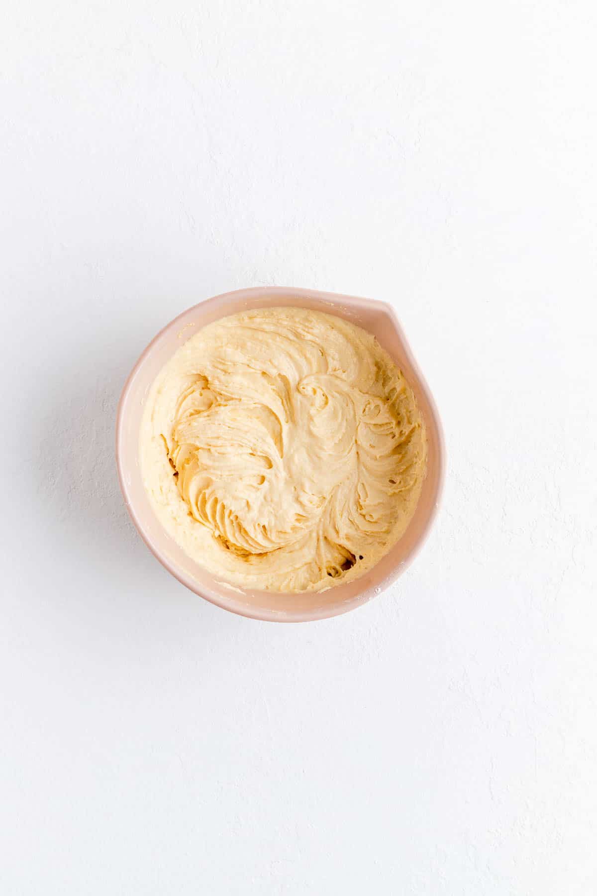 prosecco cupcake batter just mixed in a tan bowl on white background.