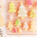 Frosted and frosted and decorated Christmas tree sugar cookies on a copper wire rack