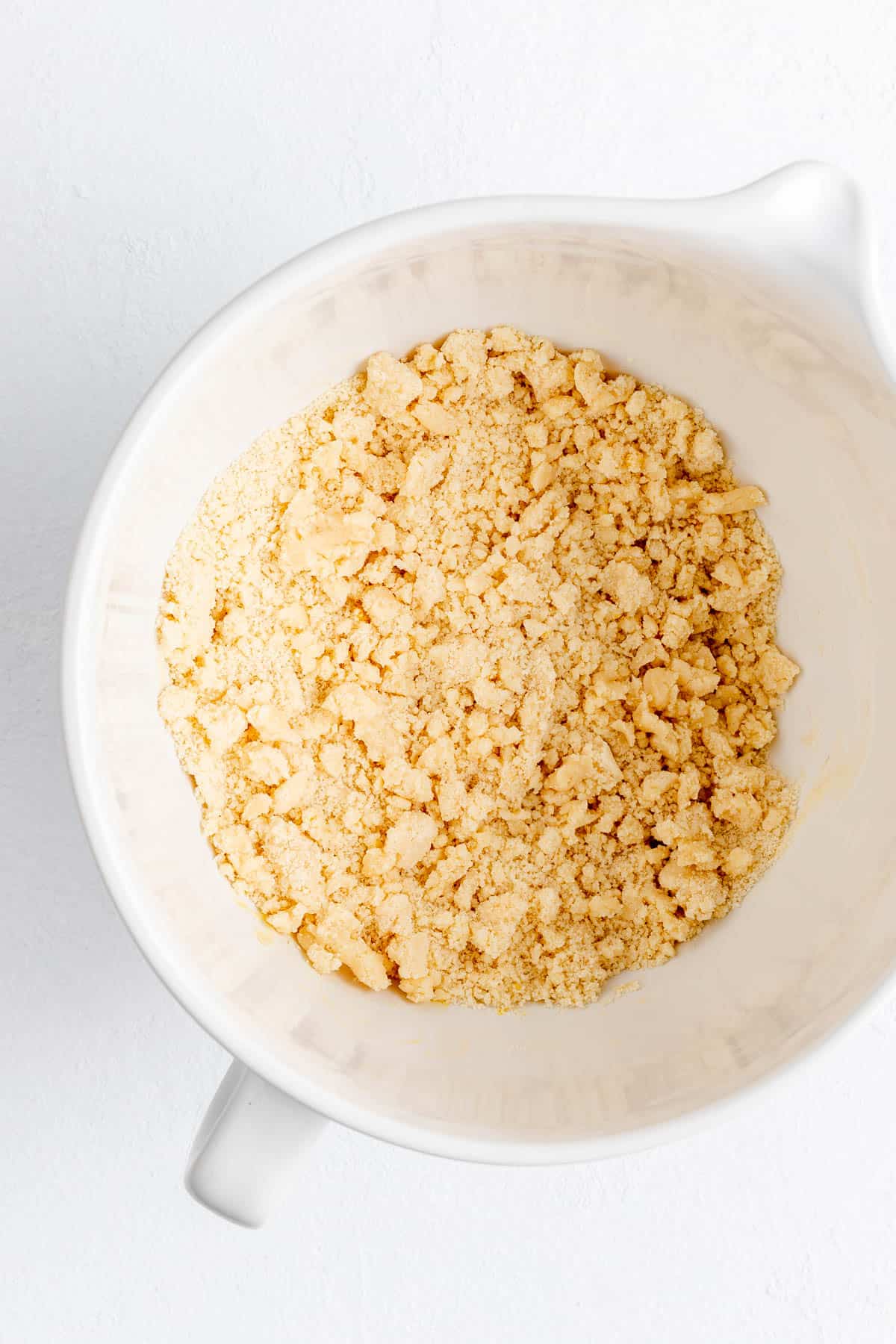 Butter and dry ingredient crumbs in a white mixing bowl per short bread dough.