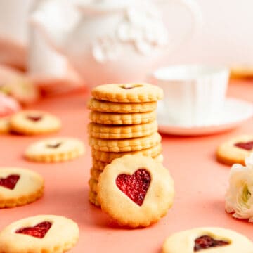 stack of jammy dodgers with one facing the camera and a teapot in the background.