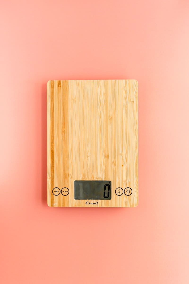 Bamboo scale reading 0 grams on coral background.