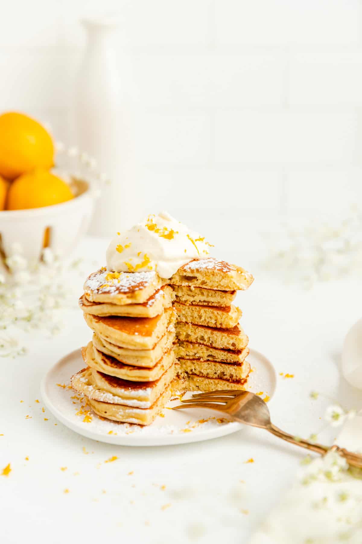 Stack of lemon pancakes with full bite out of the stack and fork on the plate.