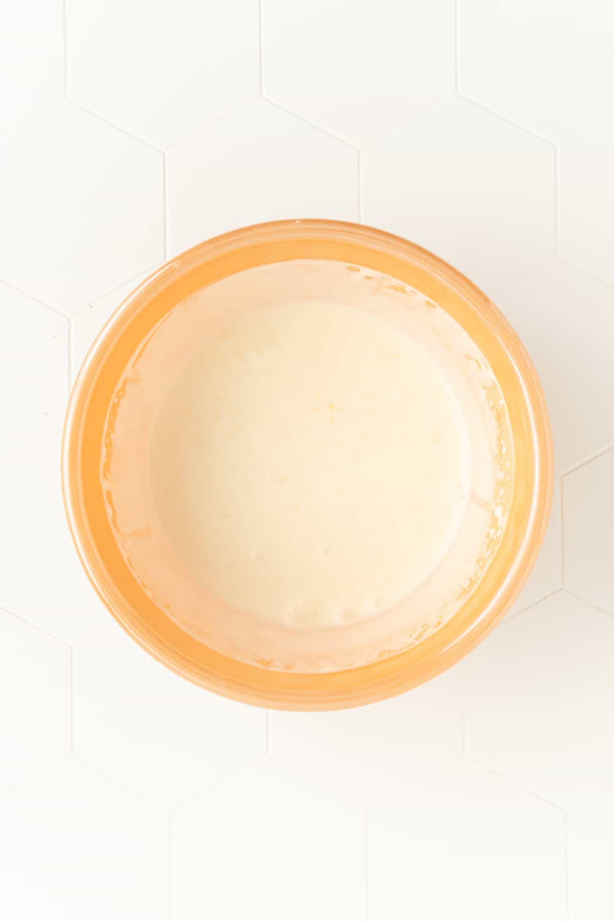 liquid fresh lemon whipped cream mixture in the orange mixing bowl