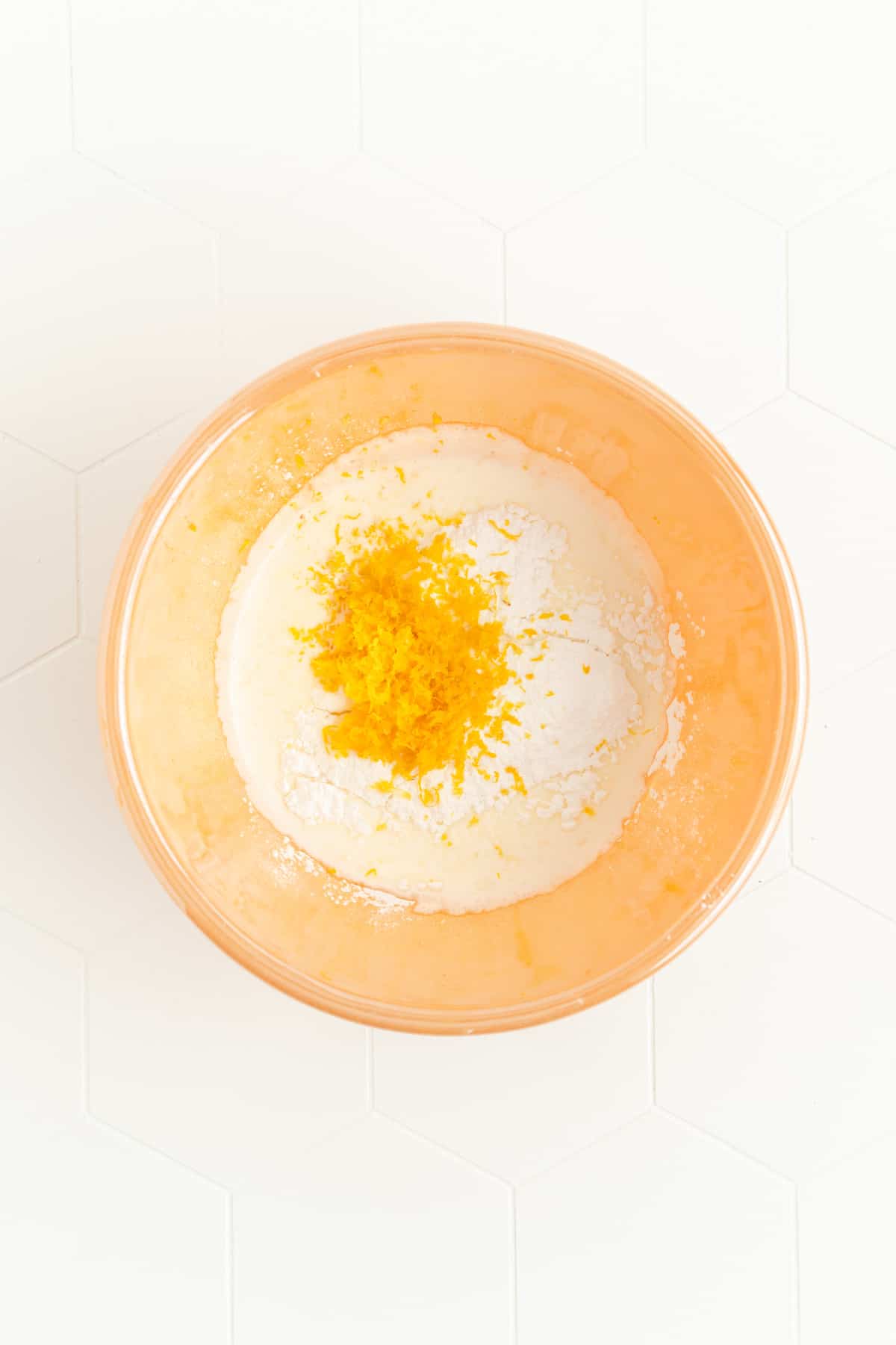 ingredients for fresh lemon whipped cream in an orange mixing bowl
