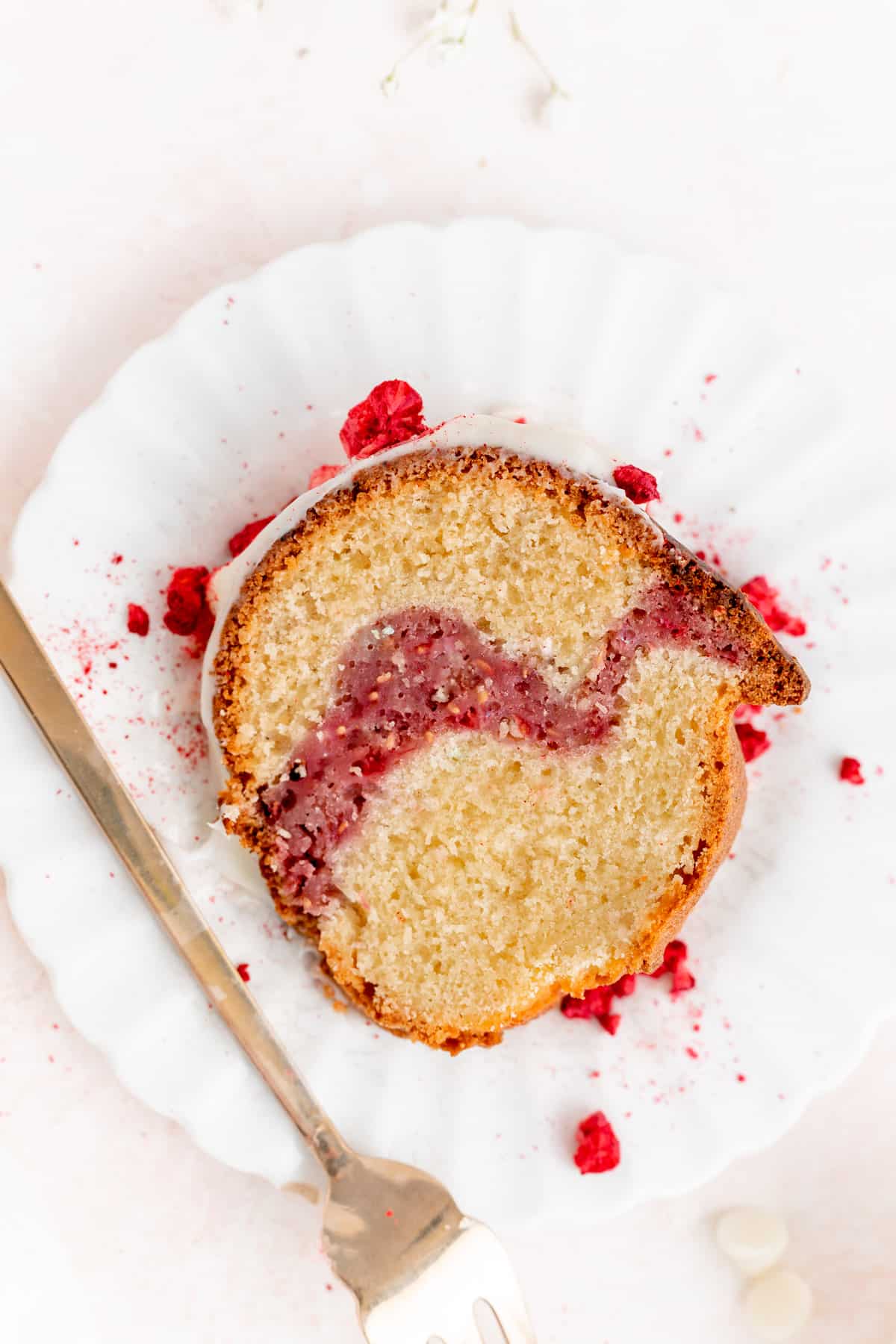 Close up overhead of a slice of white chocolate raspberry Bundt cake showing raspberry swirl.