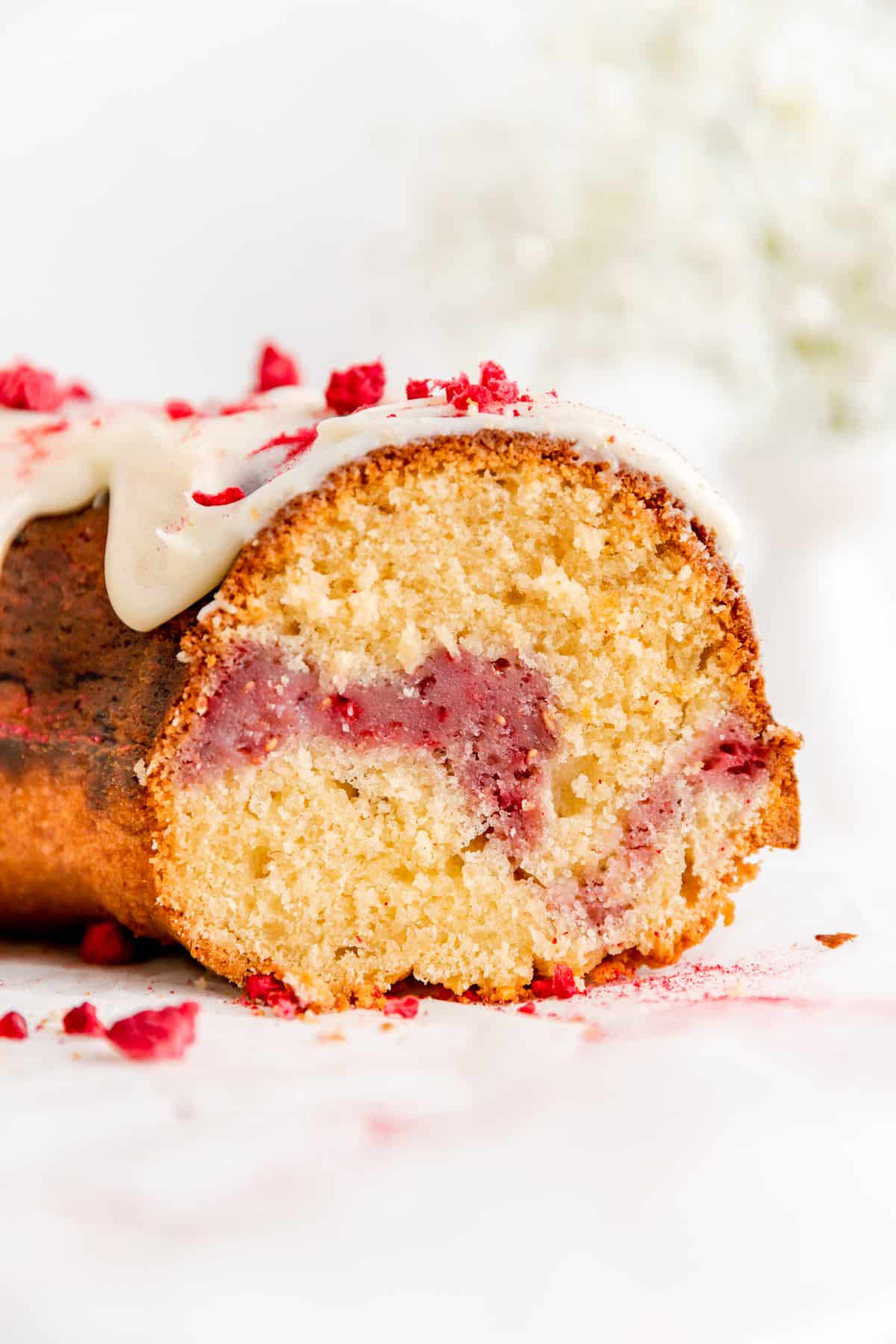Close up of cross-section of sliced Bundt cake with white chocolate sauce showing raspberry swirl.