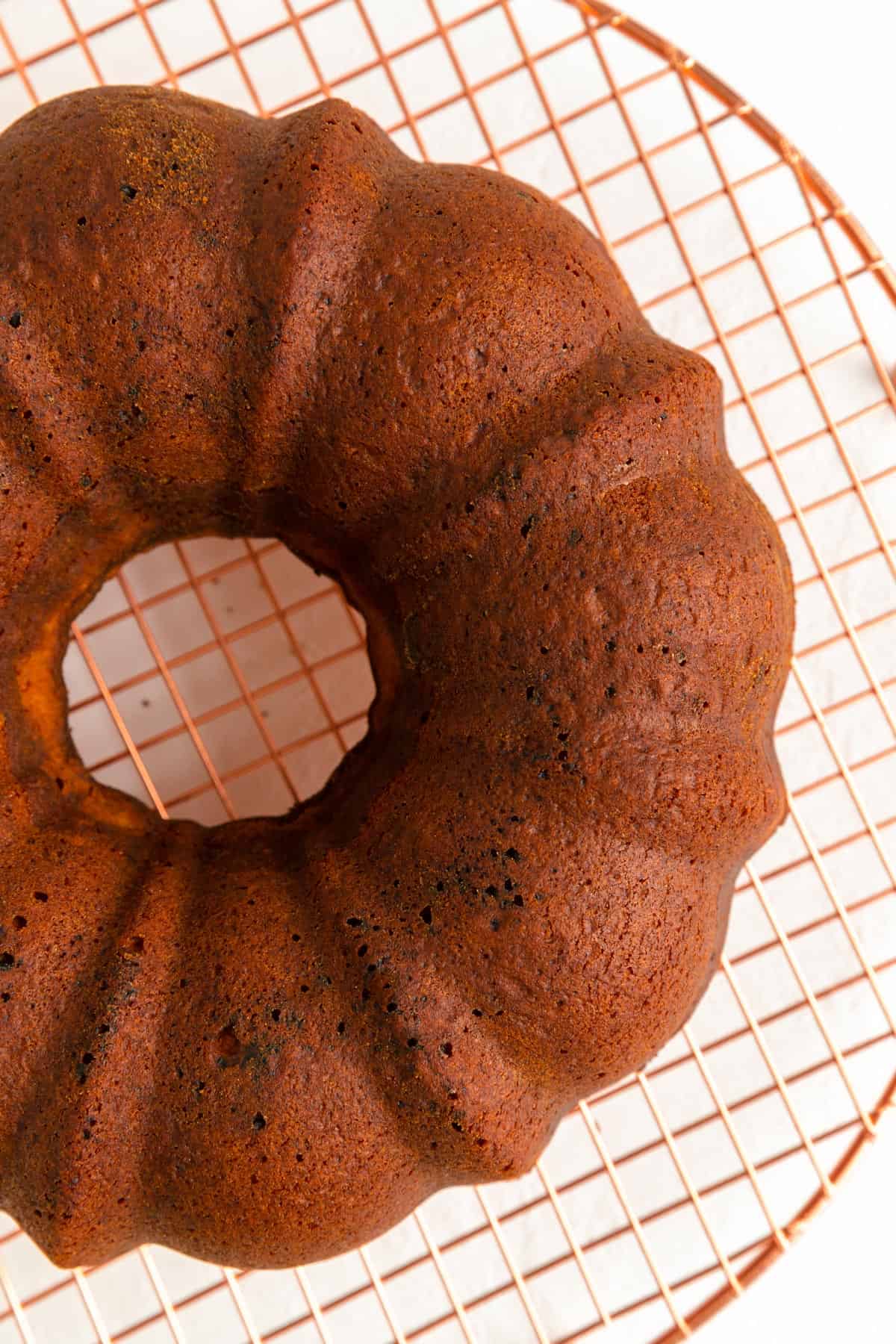 Baked raspberry white chocolate Bundt and copper wire rack shot from above.