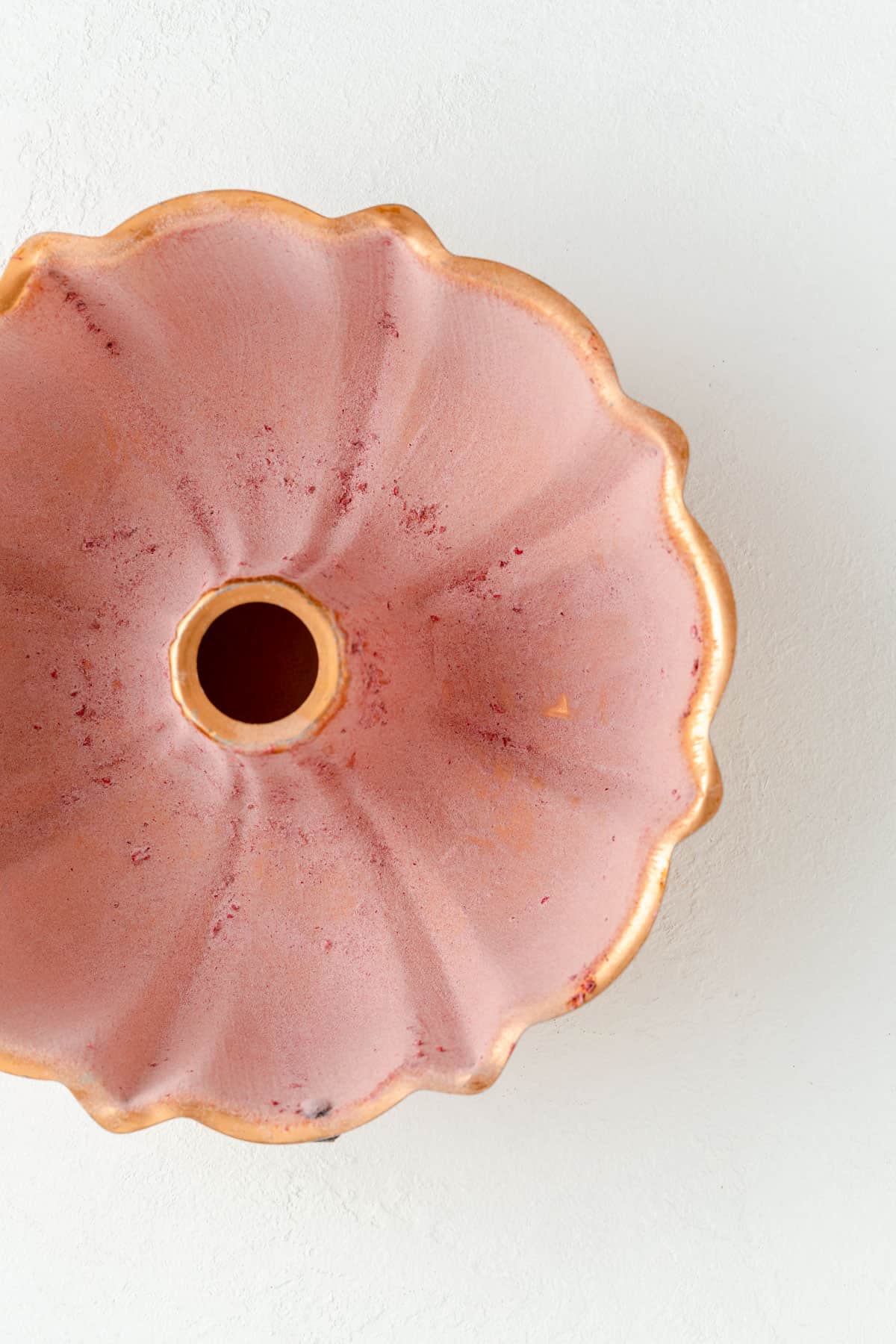 Raspberry flour dusted copper Bundt pan on a white background.