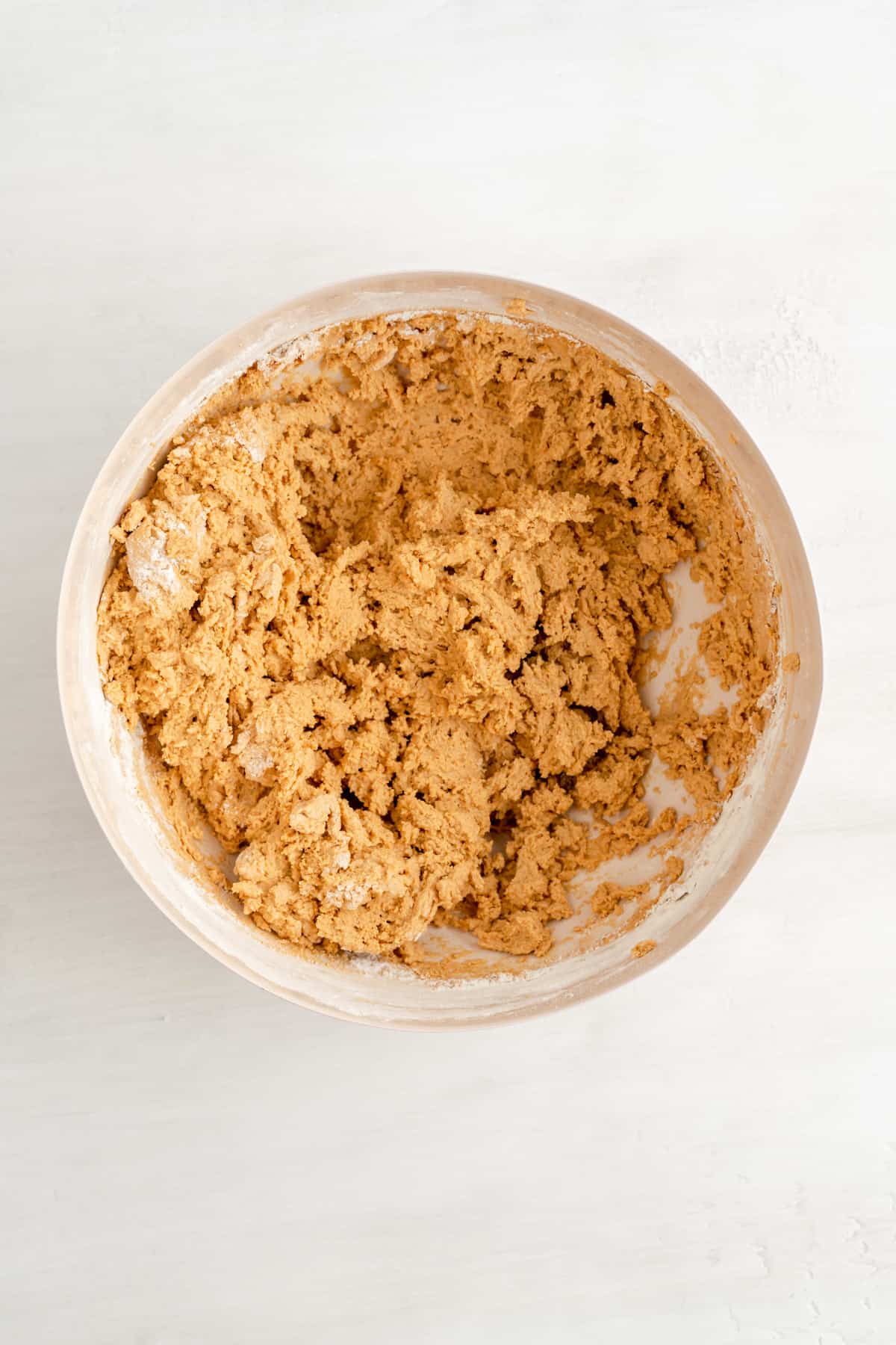 a mixing bowl of biscoff cookie dough with flour mixed into batter 80% of the way.