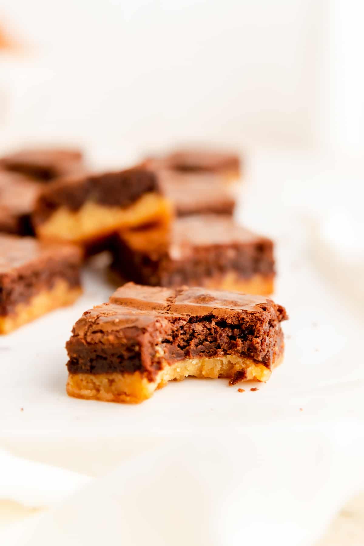 A close-up of a brownie blondie with a bite out and other bars in background.