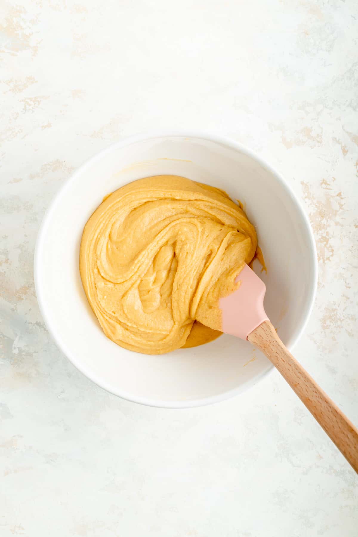 Blondie batter in a white bowl with a pink and wood spatula.
