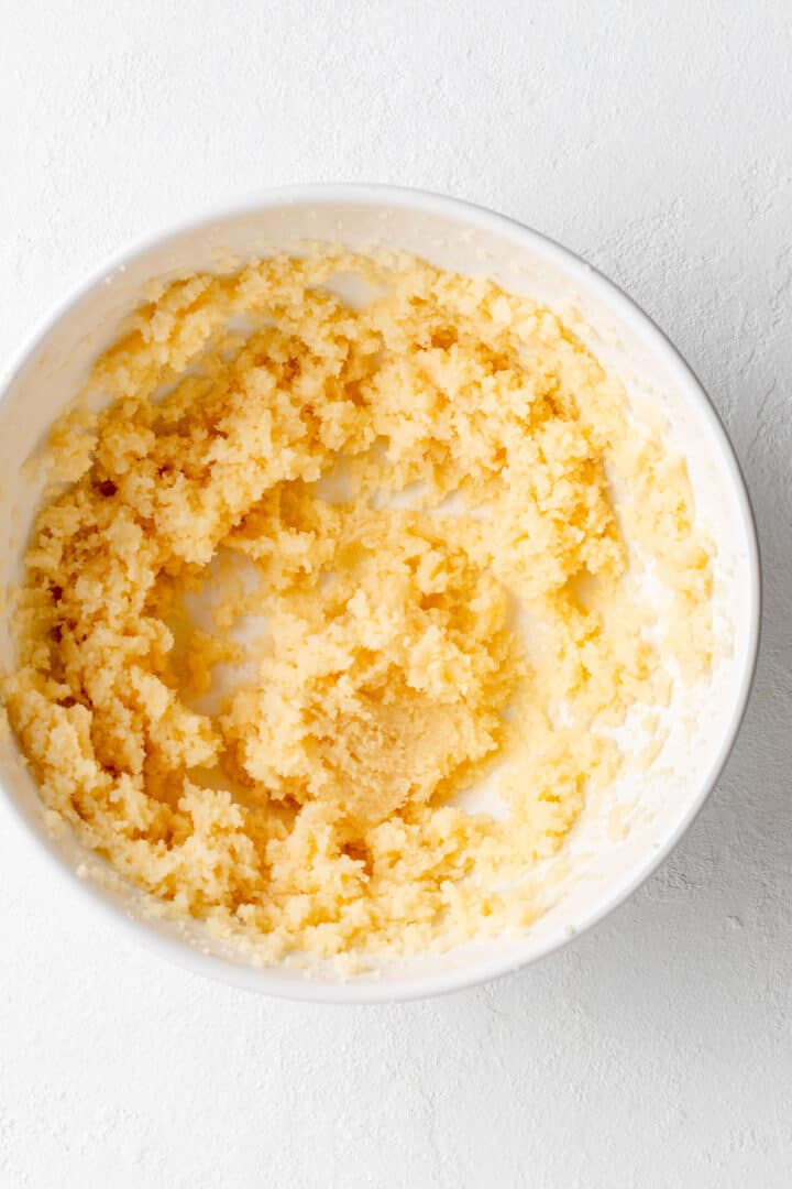 creamed butter and sugars in a white mixing bowl on a white background.