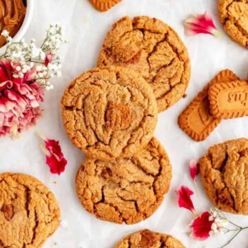 biscoff butter cookies from above with carnations, petals, and baby's breath on white background.