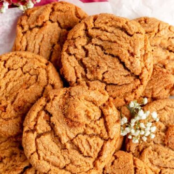 pile of biscoff butter cookies with carnations and baby's breath.