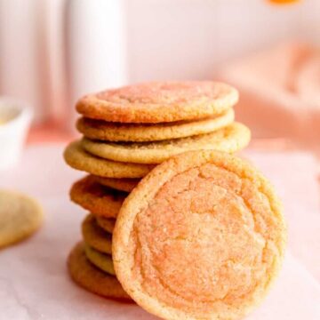 stack of pink orange and yellow sugar cookies with one cookie leaning upright against it.