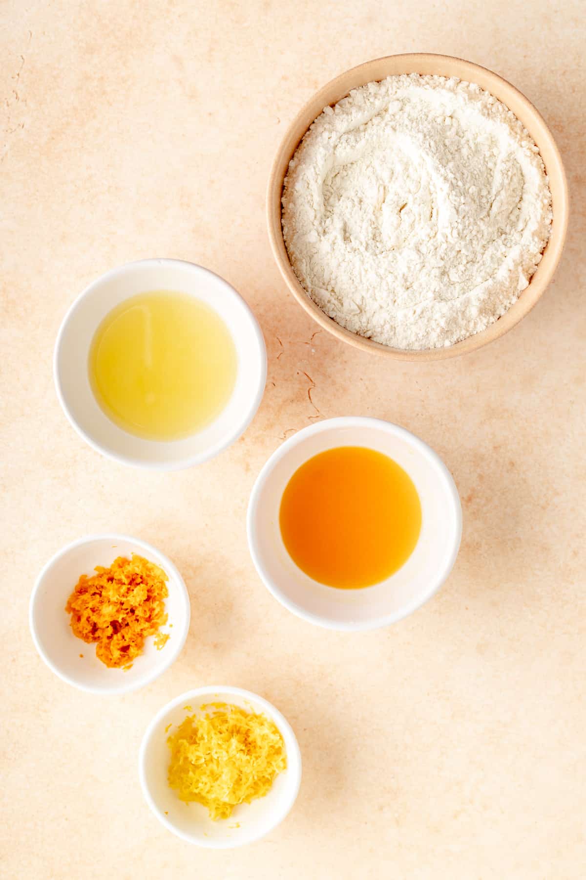 a flour mixture, lemon and orange juice, and lemon and orange zest in individual bowls.