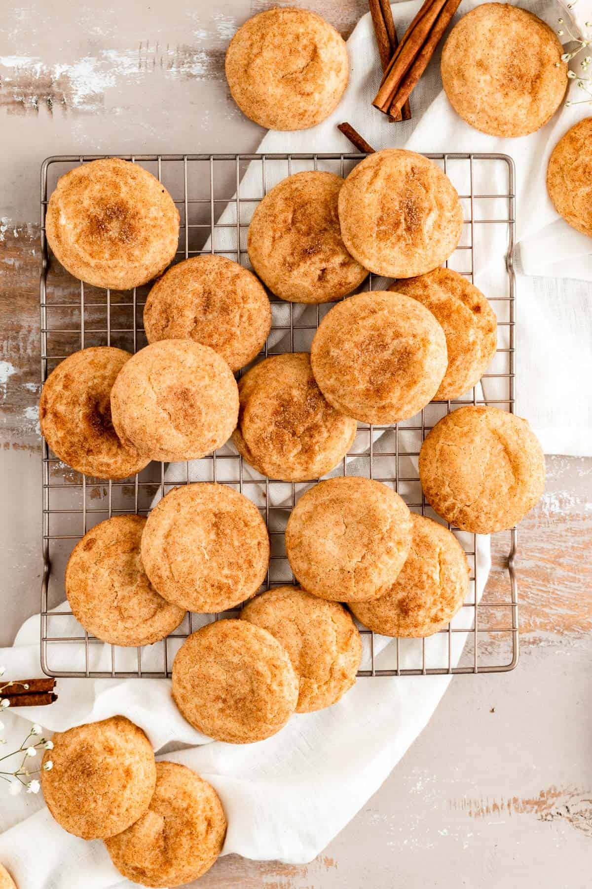 snickdoodle cookies scattered on a gold cookie sheet over white linen and light painted wood.