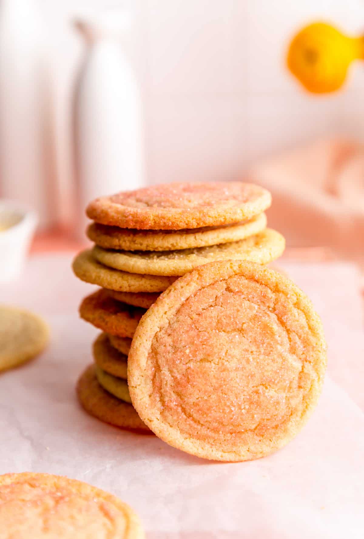 stack of pink orange and yellow sugar cookies with one cookie leaning upright against it.