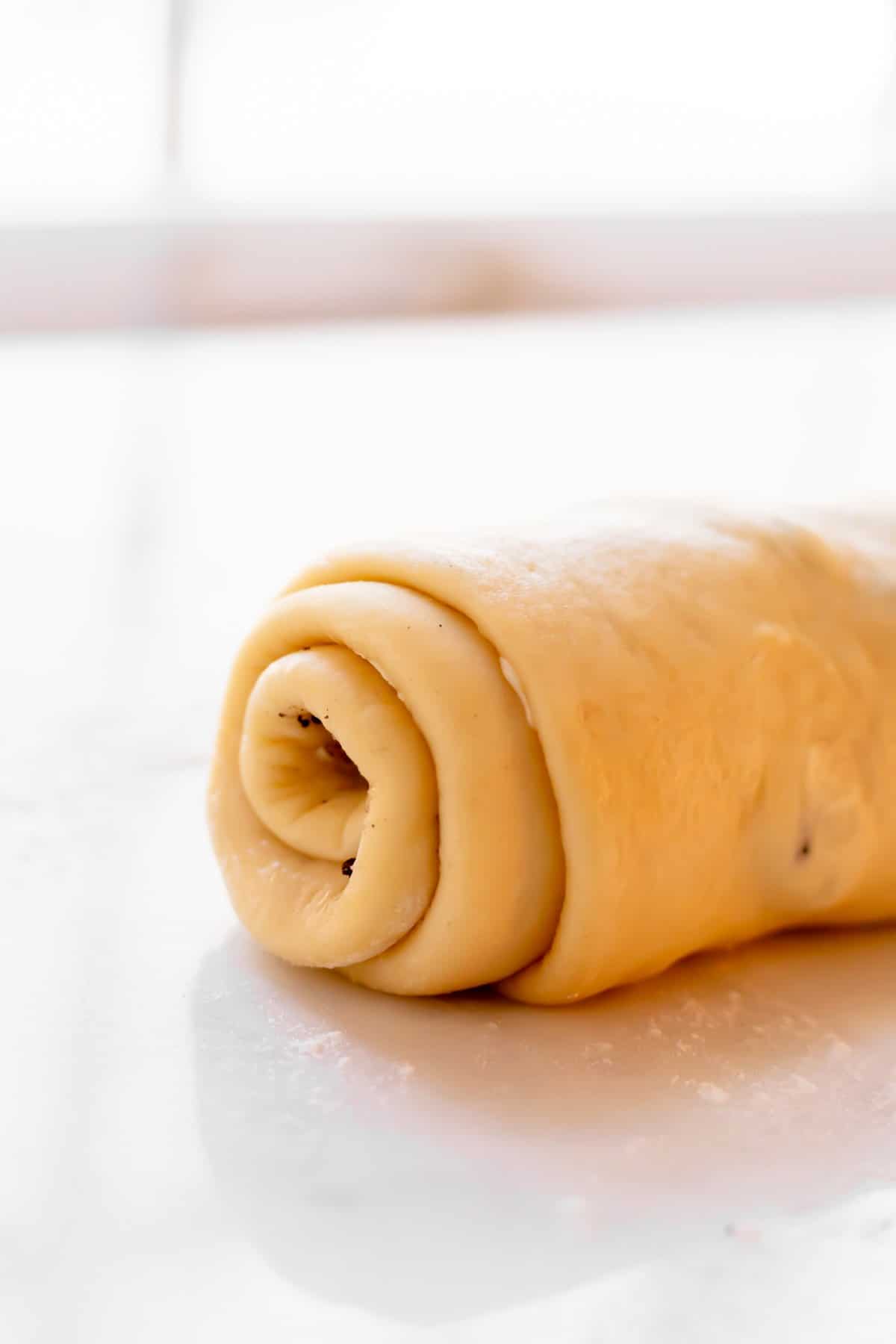 Close-up of the end of the roll the log of cinnamon roll dough with filling.