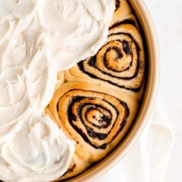 Overhead of gold pan filled with partially frosted baked Oreo cinnamon rolls.