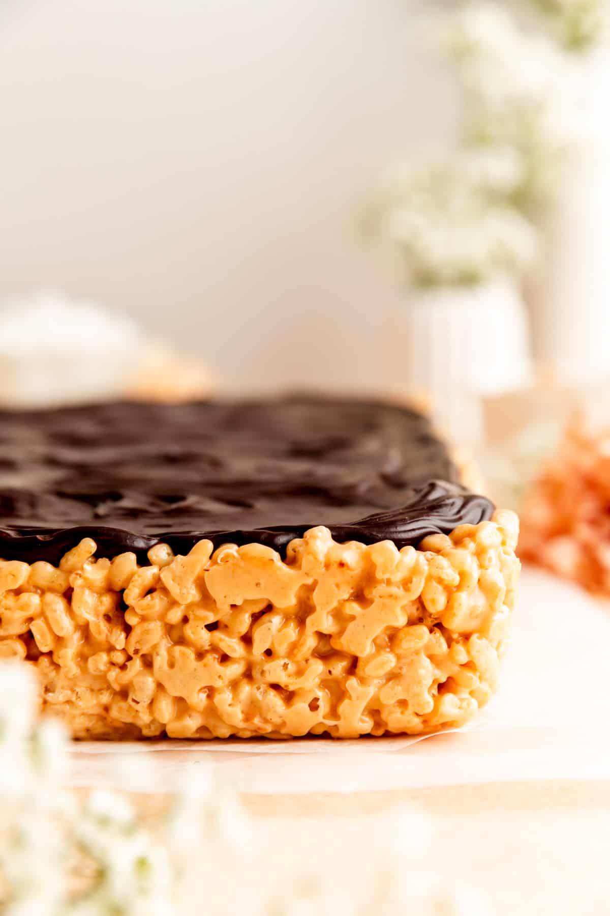 Side shot of a full block of peanut butter rice crispy treats with chocolate ganache.