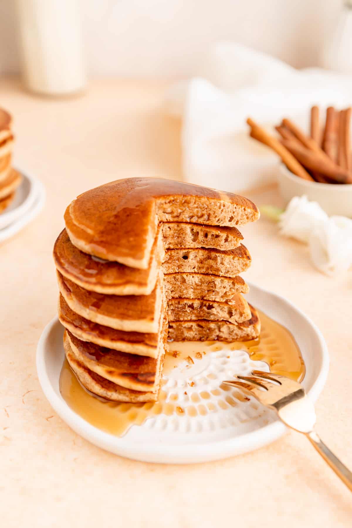 Side view of six pancakes stack with corner cut out and syrup dripping down.