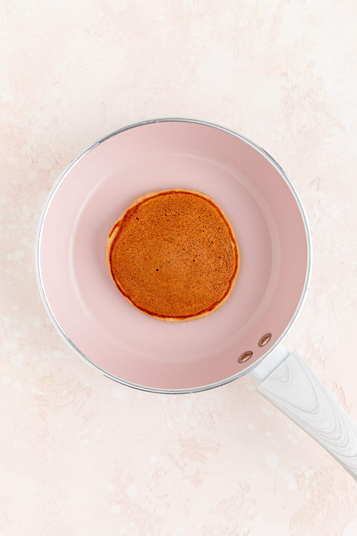 A French toast pancake cooked on top and pink pan.