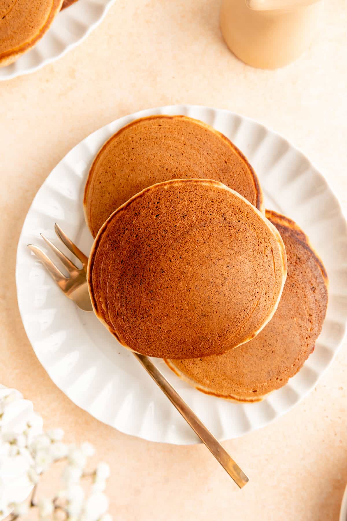 Overhead view of cinnamon pancakes and white plate with gold fork.